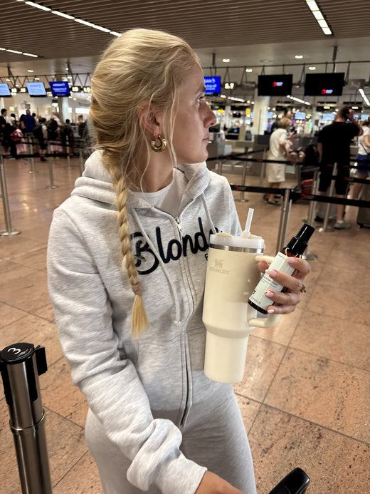 Blondie a l'aeroport en sweat Blondie, gourde et spray eclaircissant en main